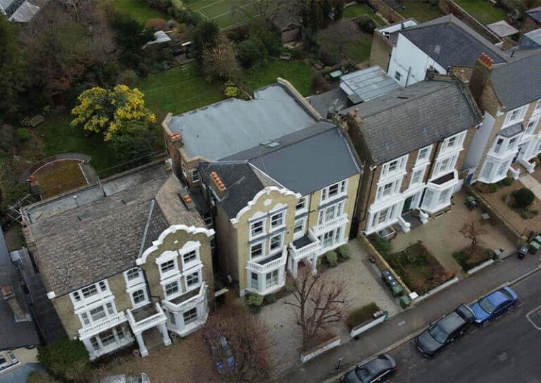 Aerial view of Georgian houses in London showcasing distinctive architectural features, including sash windows and ornamental facades, surrounded by well-maintained gardens and parked cars.