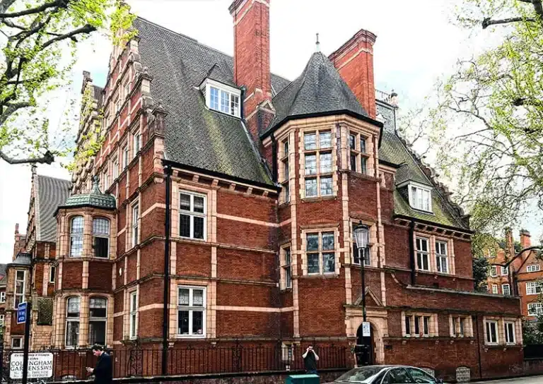 Edwardian-style brick building featuring intricate architectural details, large windows, and a steeply pitched roof, surrounded by trees, representing restoration expertise by Environ Restoration Services.