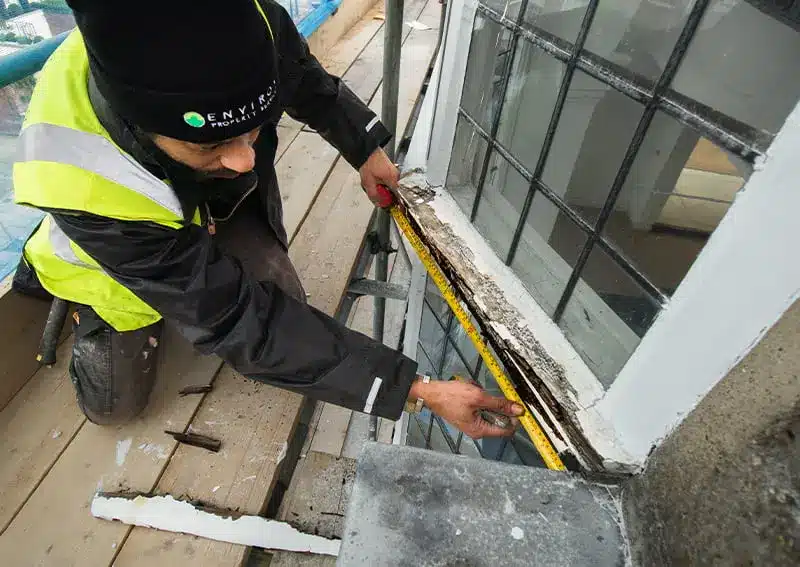 Sash window repair specialist measuring timber frame, focusing on restoration techniques and compliance with conservation standards.