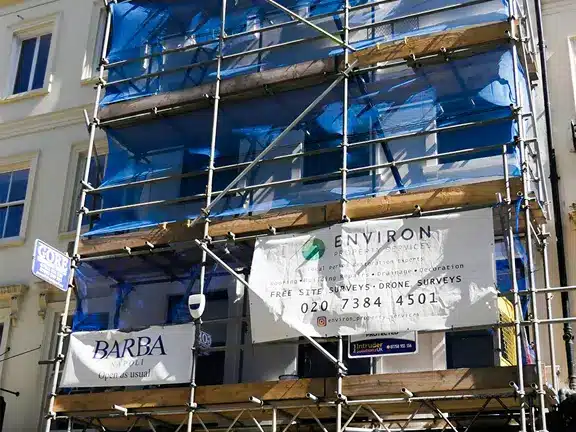 Scaffolded building with Environ Restoration Services banner, showcasing ongoing Section 20 works for property maintenance in London.