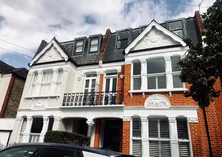 Victorian house exterior showcasing restored architectural features, including ornate detailing, a decorative balcony, and a blend of brick and white render, reflecting Environ Restoration Services' expertise in preserving historic charm.
