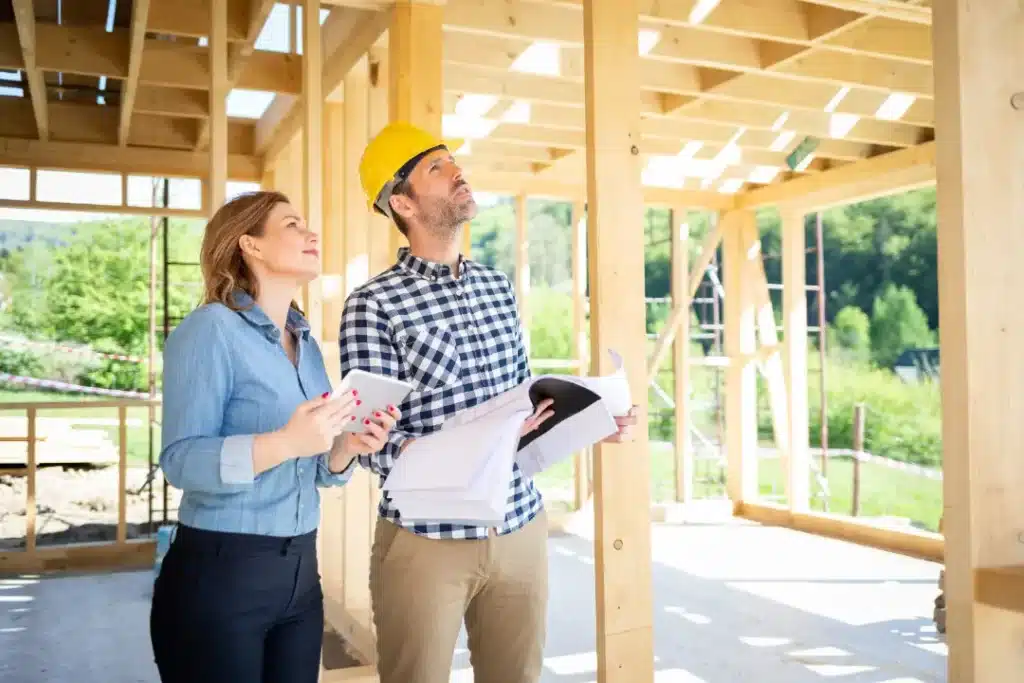 Two professionals examining architectural plans in a partially constructed building, focusing on restoration and renovation processes.