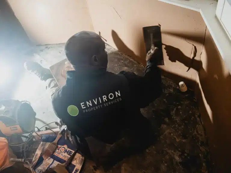 Professional worker from Environ Property Services applying damp treatment to wall in London home, highlighting expert damp proofing solutions.