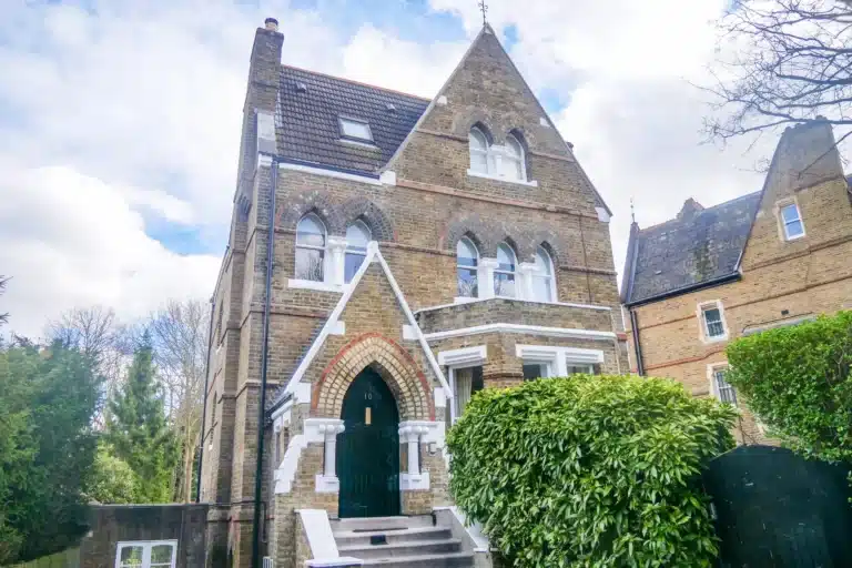 Victorian house exterior featuring intricate brickwork, arched windows, and a welcoming entrance, surrounded by lush greenery, illustrating the restoration expertise of Environ Restoration Services.