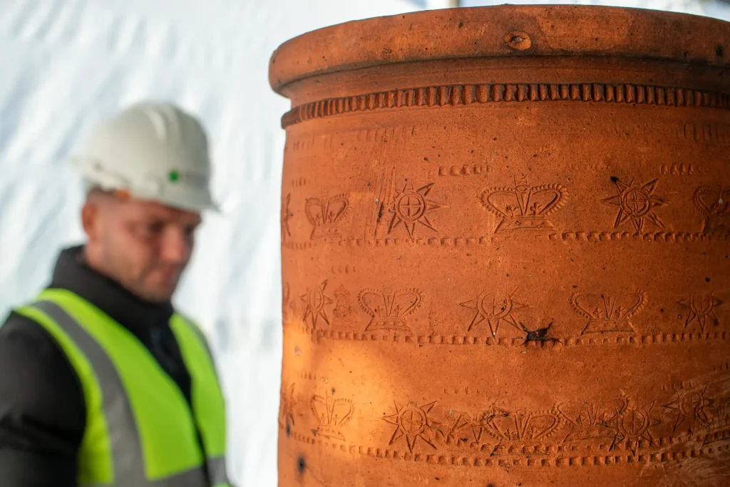 Archaeologist examining intricately designed terracotta pot with historical engravings, showcasing dedication to cultural heritage preservation in restoration services.