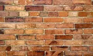 Close-up of a brick wall showcasing various shades of red and brown bricks, highlighting the texture and condition relevant to masonry inspections and winter repointing practices for preserving London properties.