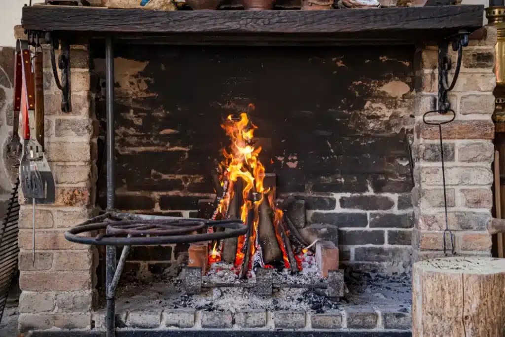 Brick fireplace with flames, surrounded by cleaning tools, illustrating effective methods for maintaining and cleaning fireplace bricks.