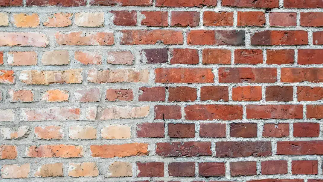 Brick wall showcasing a mix of weathered and clean bricks, illustrating the importance of regular maintenance and cleaning for structural integrity and visual appeal.