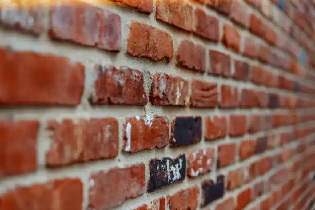 Close-up of a textured brick wall showing various stains and discoloration, highlighting the need for effective cleaning methods to preserve brick integrity and appearance.