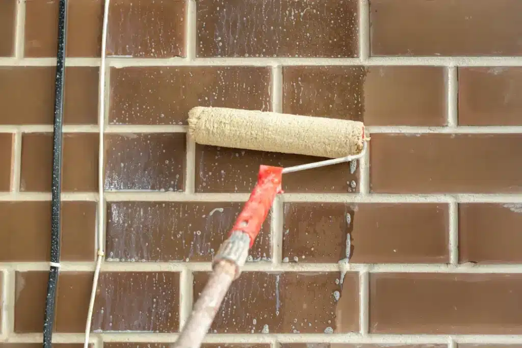 Brick cleaning process with a roller applying cleaning solution to a brick wall, highlighting restoration techniques for effective maintenance.