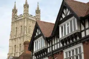 Historic building with timber framing and ornate windows, featuring a tall church tower in the background, illustrating heritage architecture and restoration.