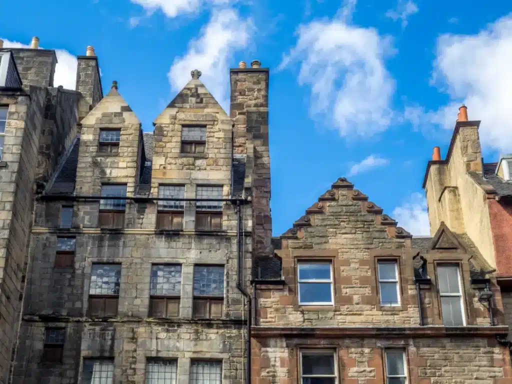 Historic buildings with distinctive stone architecture and gabled roofs under a blue sky, representing heritage properties relevant to UK conservation and restoration.